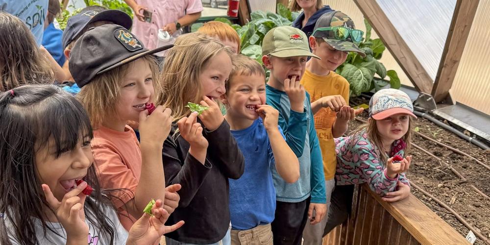 Seven young kids trying fresh beet root in a Growing Dome smiling for the camera