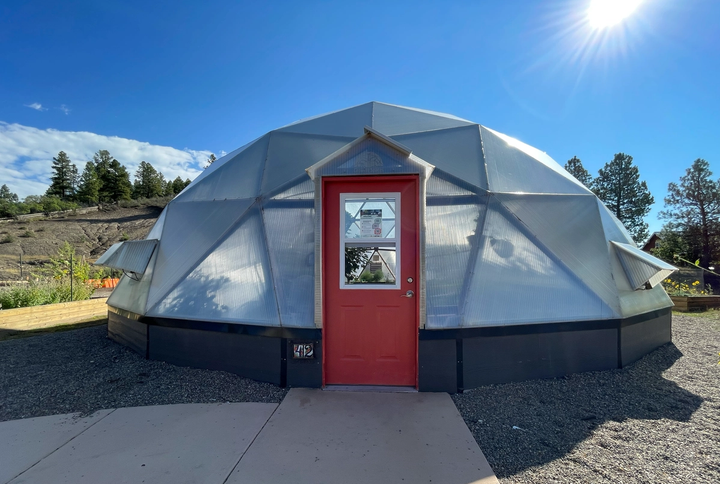 42 foot diameter Growing Dome greenhouse with red doors, blue sky, and bright sun