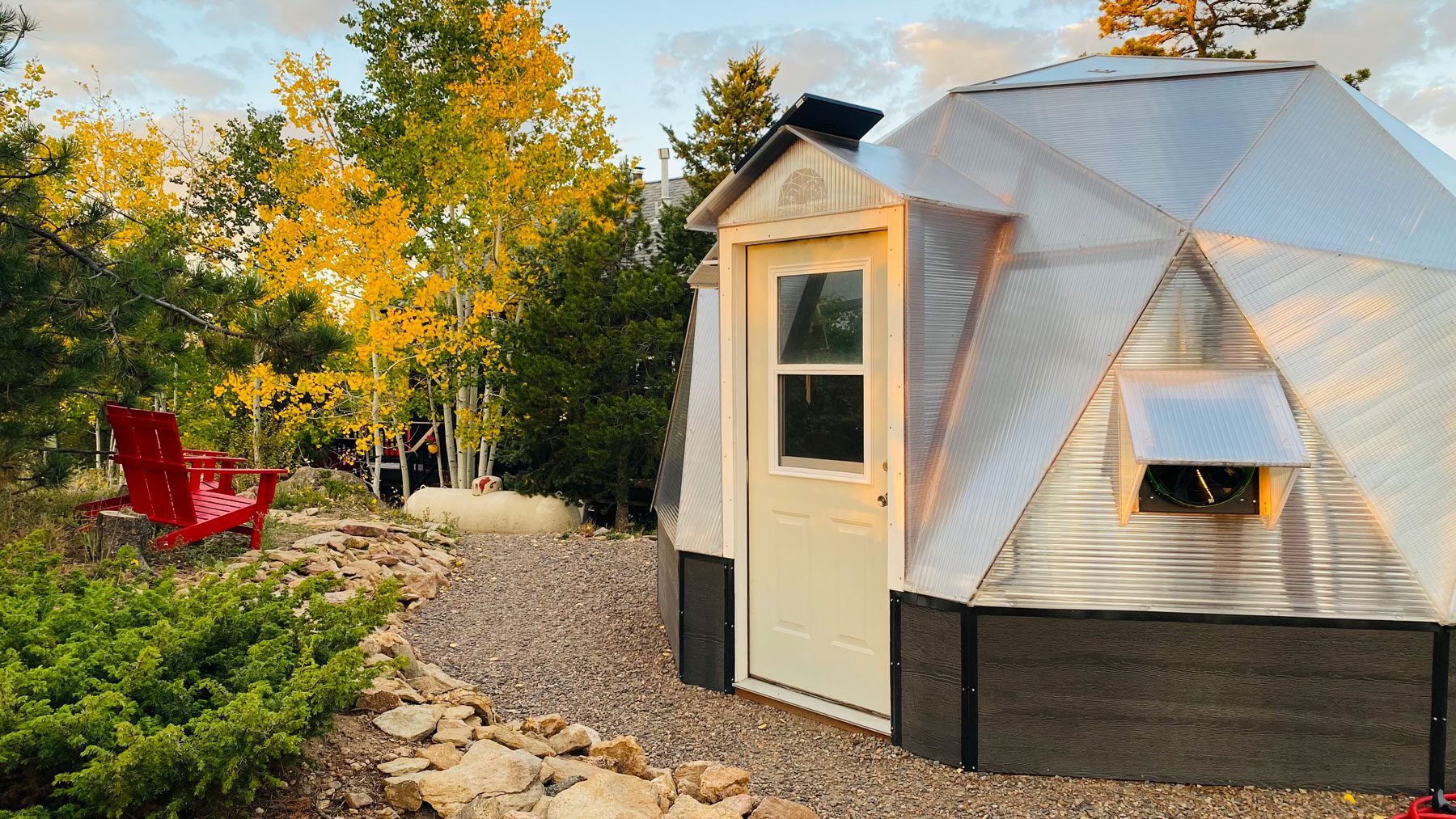 growing dome greenhouse with red adirondack chair