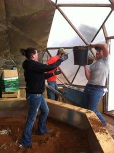 students filling greenhouse garden beds with soil