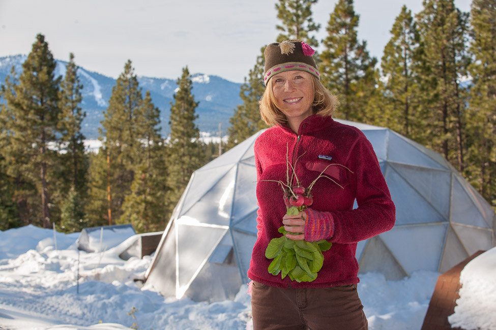 Grower holding fresh radishes beside a Growing Dome at Truckee Community Farm in California