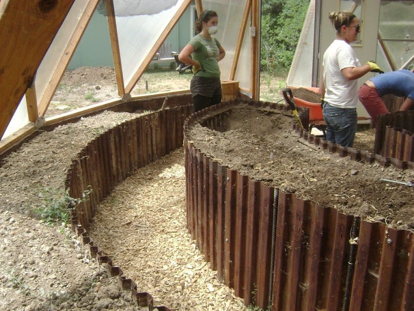 rigid corrugated metal raised beds inside a geodesic greenhouse showing different bed heights