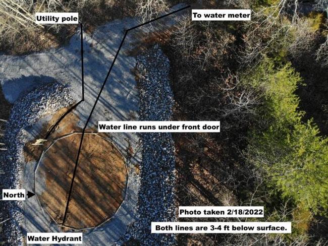 An overview of a greenhouse site with the foundation prepped and the water and electric lines highlighted
