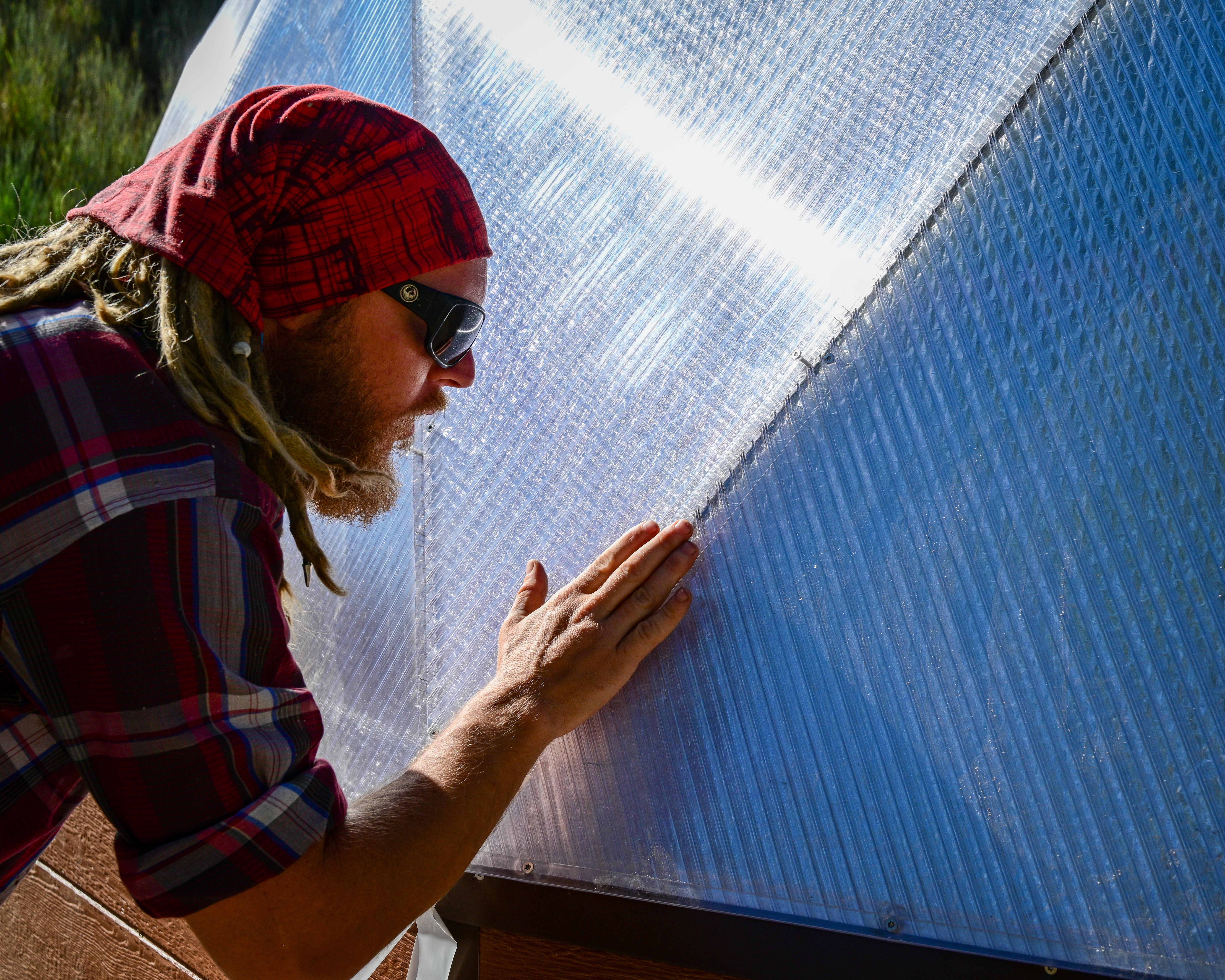 Man using his hand to apply tape to a greenhouse panel