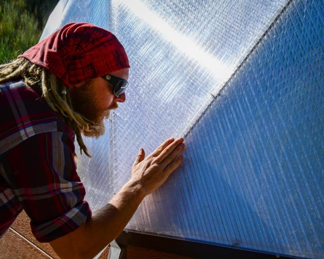 Man applying tape to polycarbonate panels with his hand