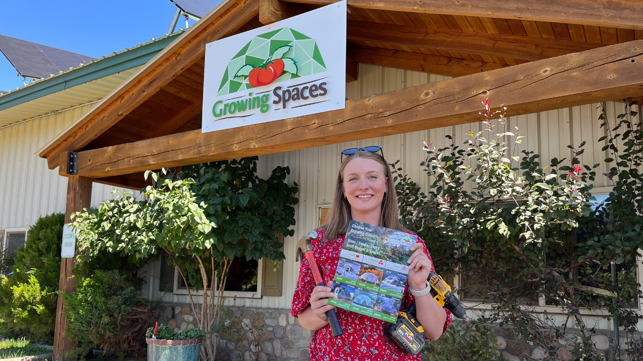 woman standing in front of a building with Growing Spaces logo she's holding tools and a flyer