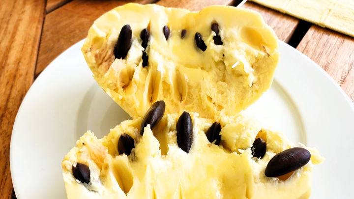 looking inside pawpaw fruit opened up to reveal the seeds sitting on a plate