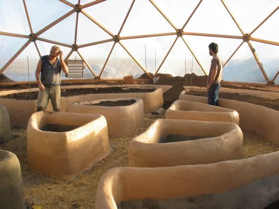 finished straw beds that are painted a light orange terracotta inside the greenhouse