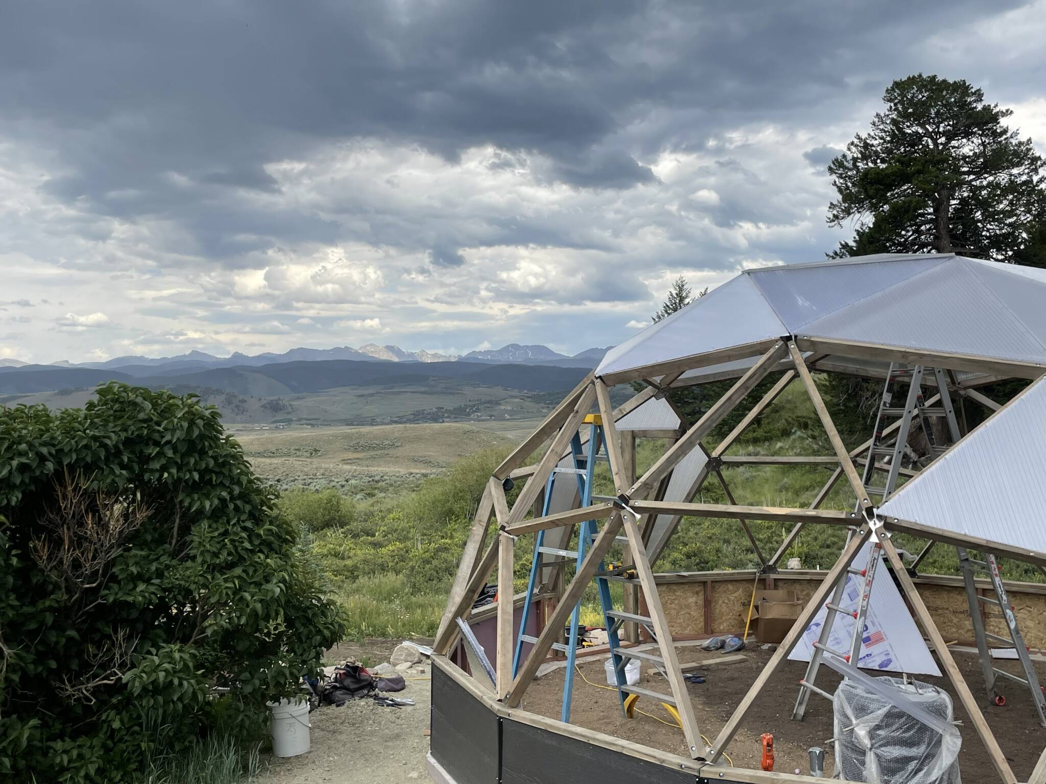 Growing Dome greenhouse during construction with mountain range in background