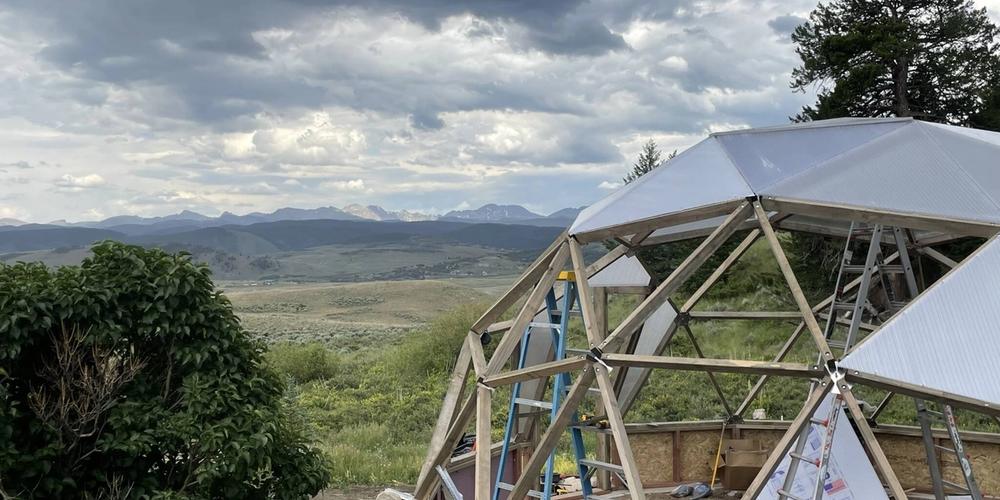 Growing Dome greenhouse during construction with mountain range in background