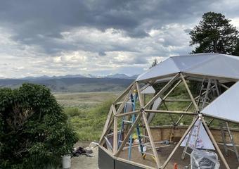 Growing Dome greenhouse during construction with mountain range in background