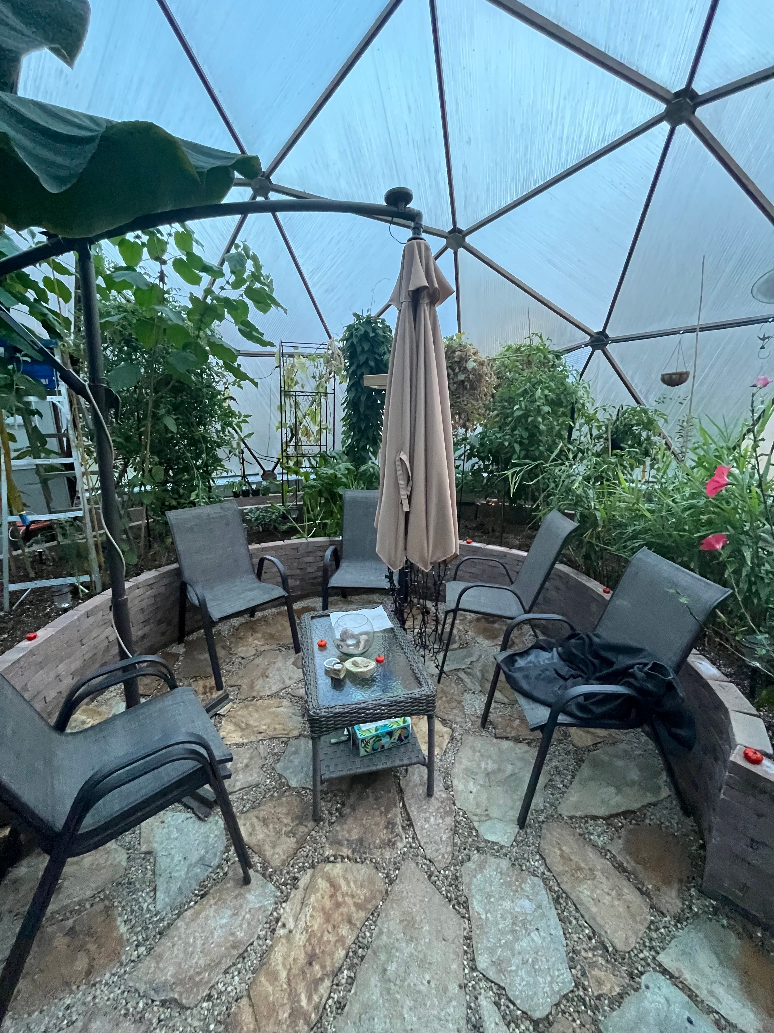 Interior seating area surrounded by stone garden beds in a Wisconsin Growing Dome greenhouse