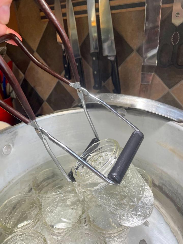 using a jar lifter to remove sterilized jars from a water bath canner