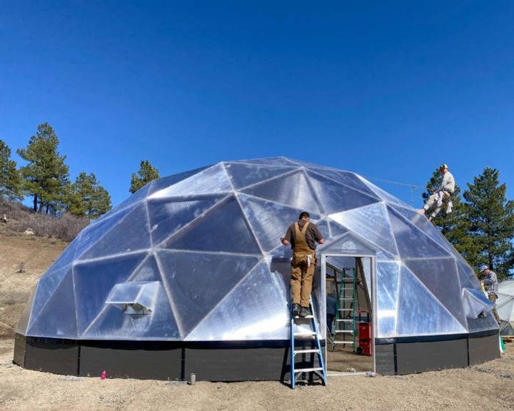 Two men applying tape to a 42' Growing Dome.