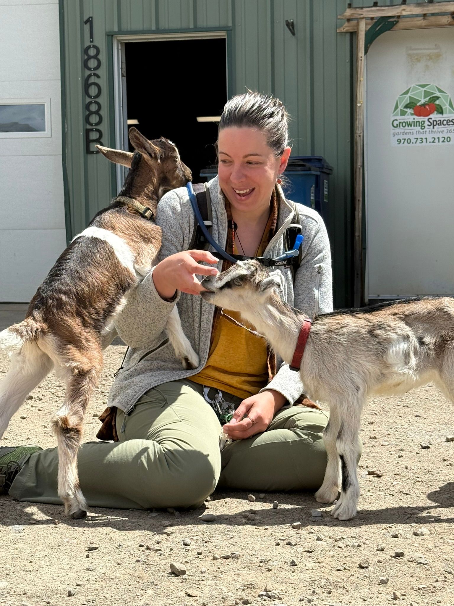 Woman adoring baby goats in front of the Growing Spaces building