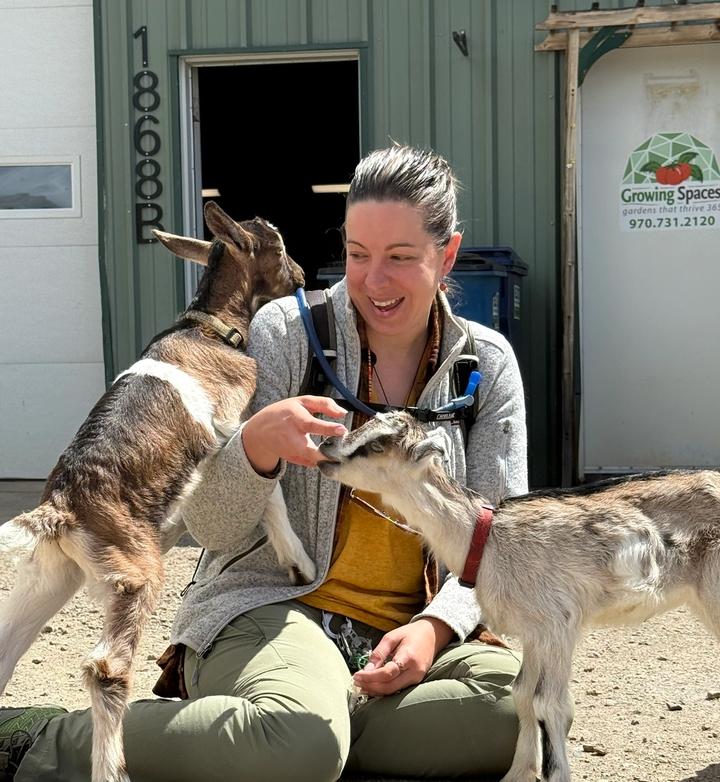 Woman adoring baby goats in front of the Growing Spaces building