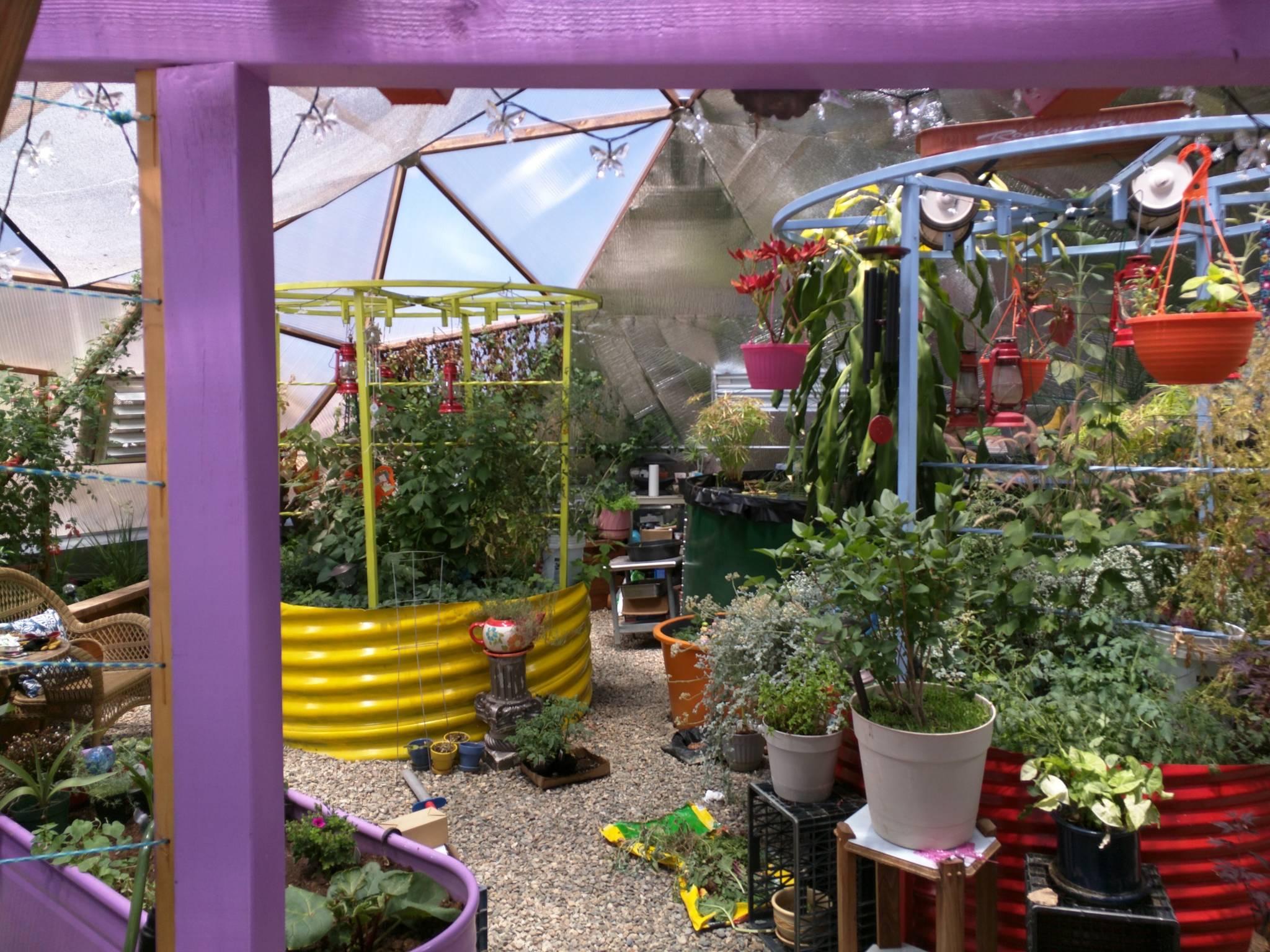 what looks like large metal tubes used for drainage are set vertically as garden beds and brightly colored yellow and red with different colored trellises