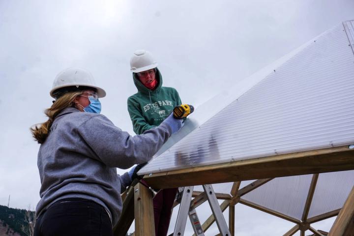 Students attaching polycarbonate to a greenhouse