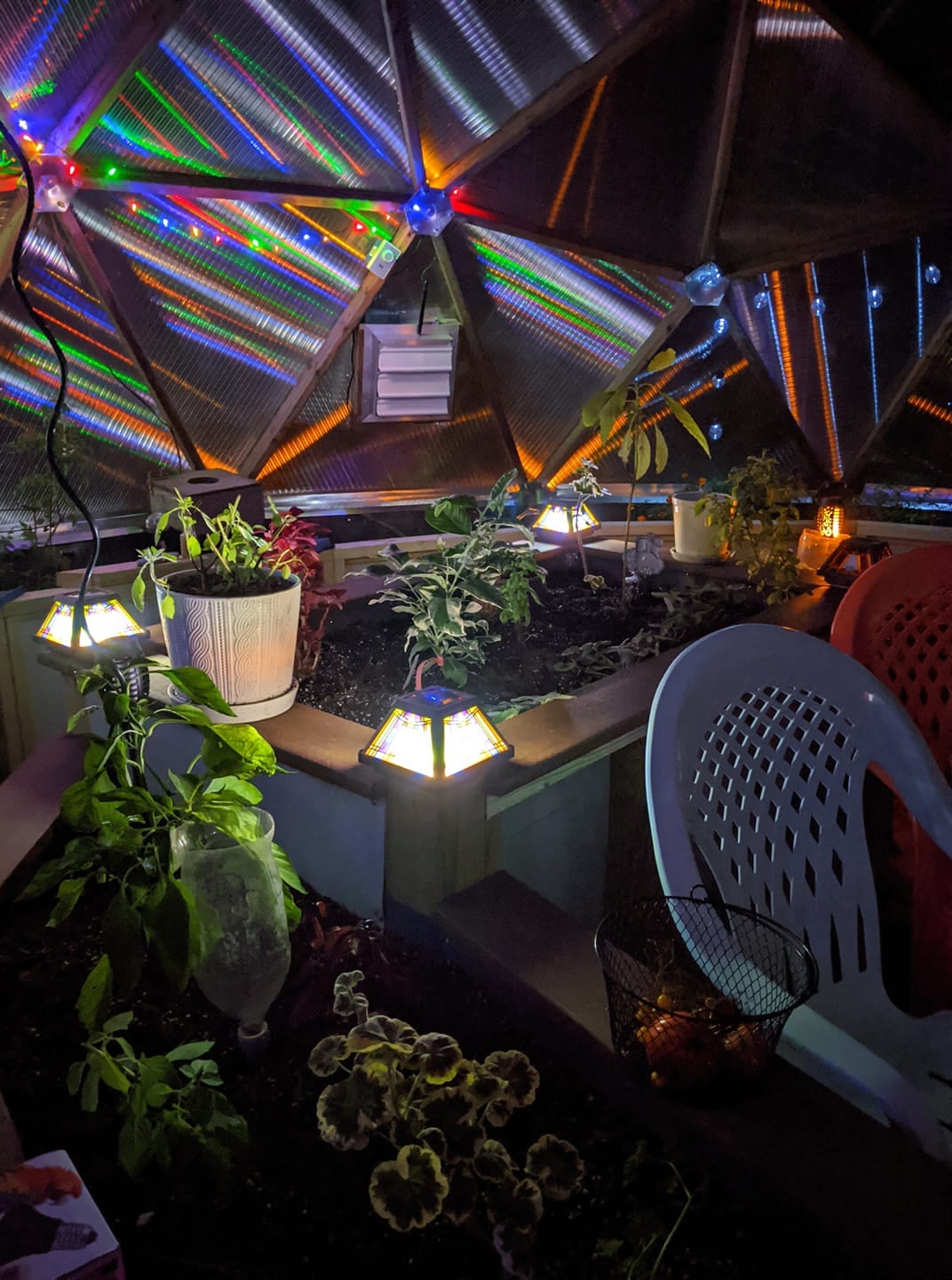 Plants, seating, and a fireplace inside a New Hampshire Growing Dome at night