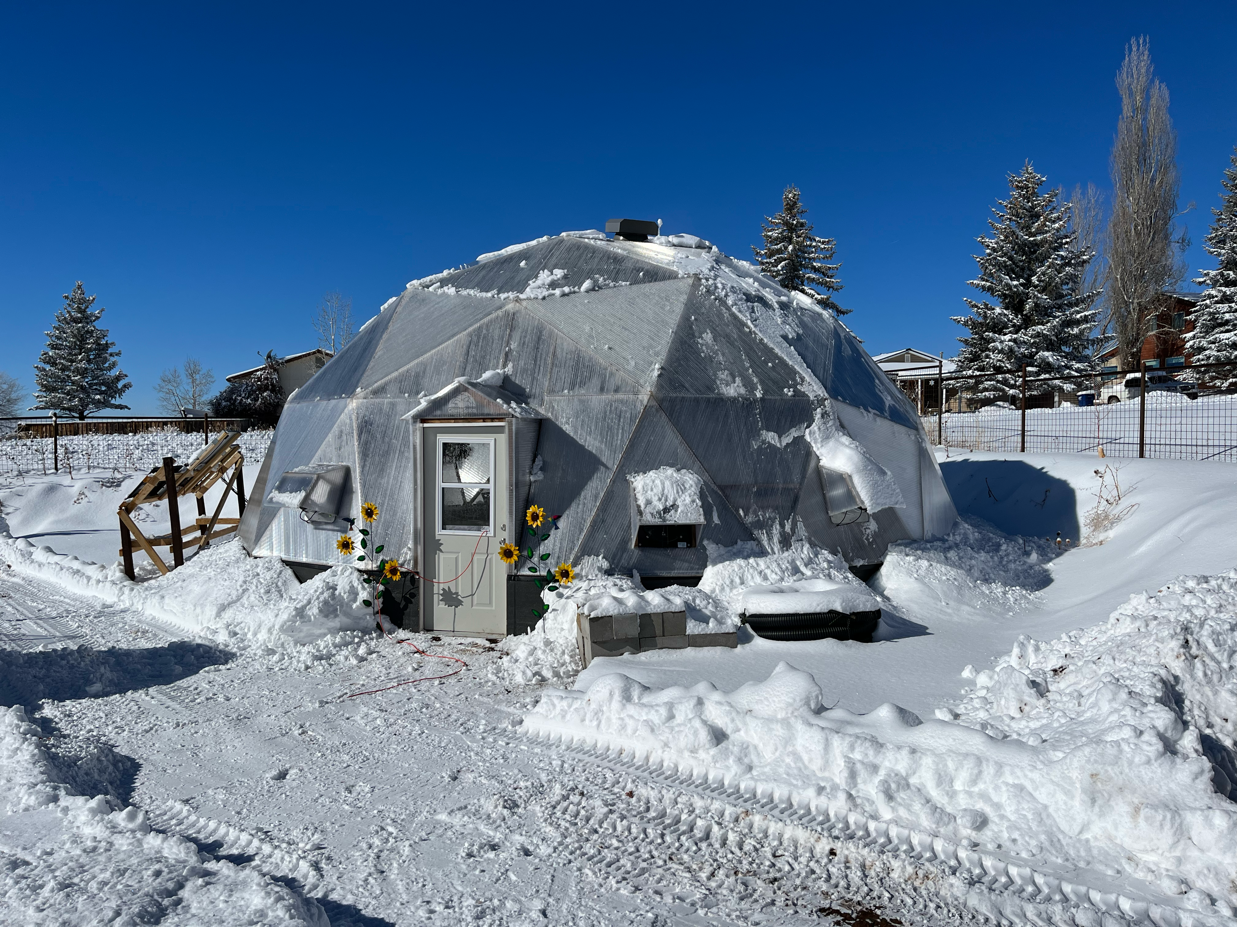 growing dome greenhouse in the snow with bluebird skies