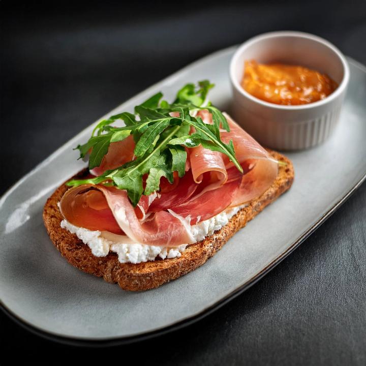 AI generated breakfast toast with goat cheese, ham, arugula, and fig jam