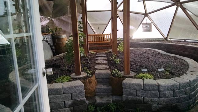looking from the doorway paver stone raised beds with paver stairway and stepping stones across the bed inside the greenhouse