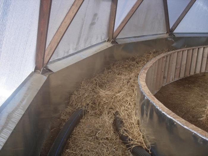 A layer of straw in the bottom of a raised garden bed with corrugated tubing running through it