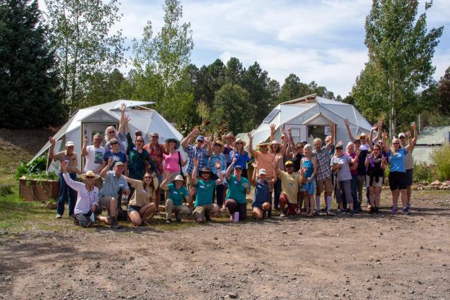 Large group of happy people standing in front of two Growing Dome greenhouse