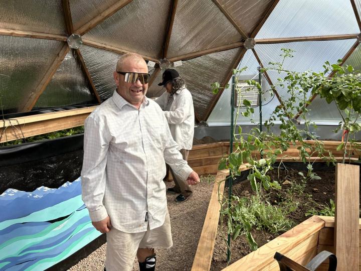 John showing off his tomatoes in a Growing Dome greenhouse for veterans at the Valor Point Domiciliary