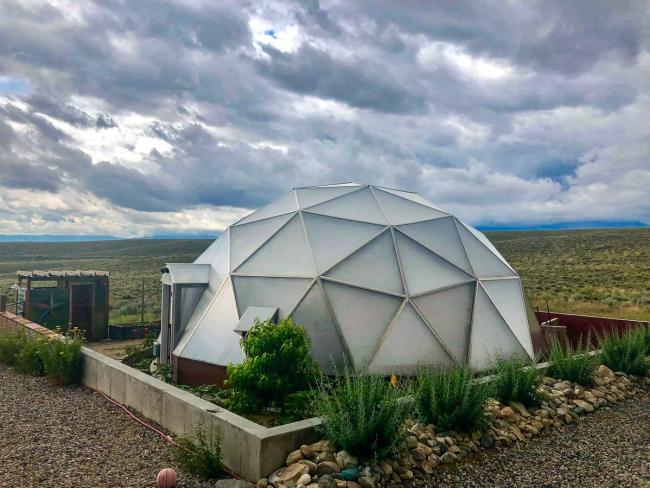 Growing Dome on an open high-desert property beneath storm clouds