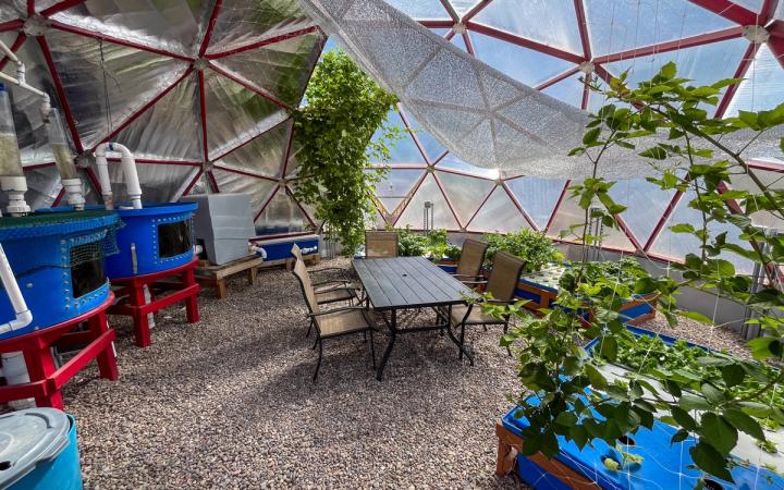 Interior of a 26' Growing Dome featuring an aquaponics system and table in center