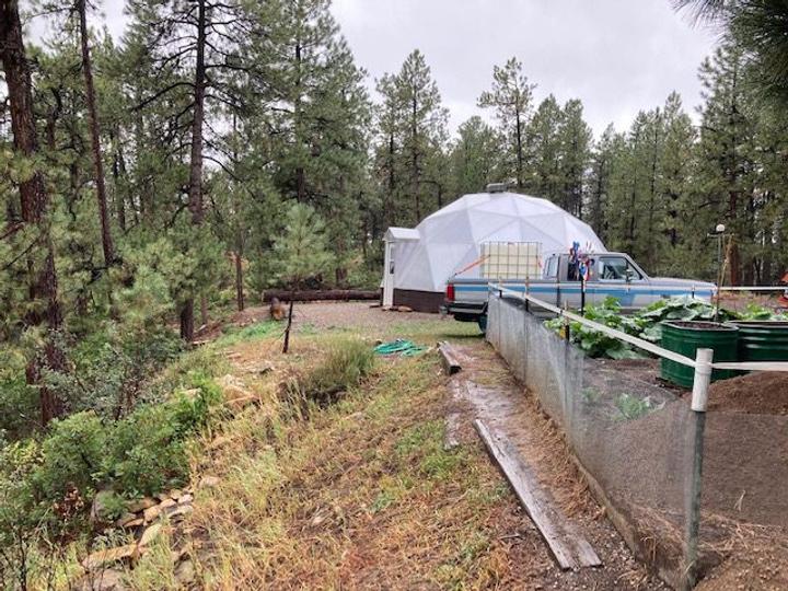 outdoor raised garden beds with a geodesic greenhouse in the background