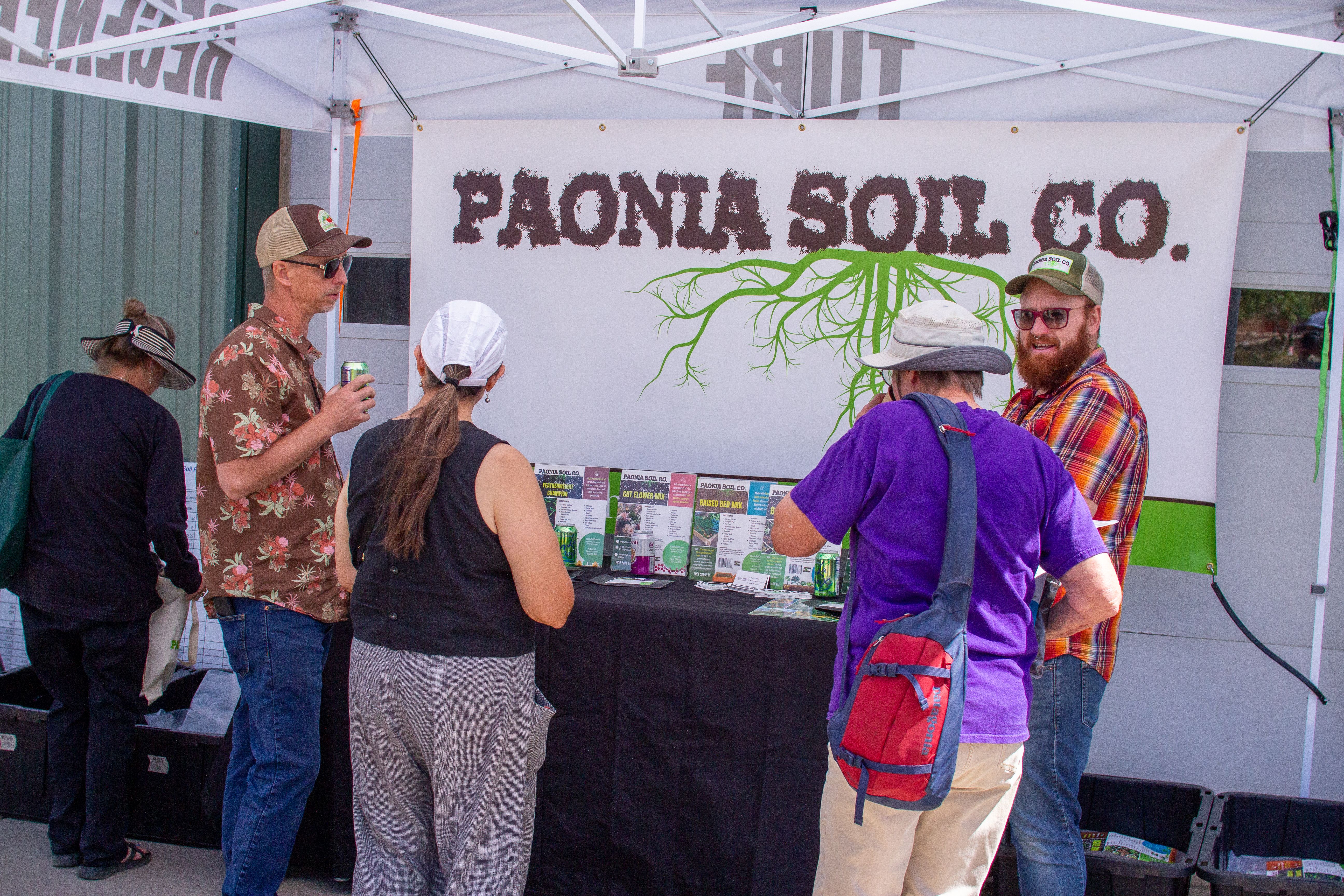People gathered around a soil booth at a gardening event