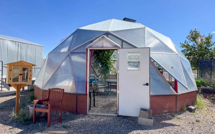 Exterior of a 26' Growing Dome with the door open revealing a passion fruit plant inside