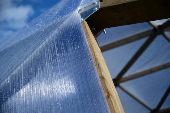 polycarbonate of a growing dome greenhouse under construction covered in rain droplets