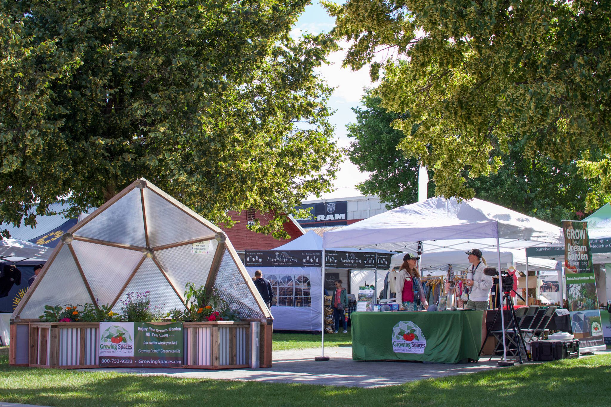 partial growing dome model and Growing Spaces booth set up outdoors under trees