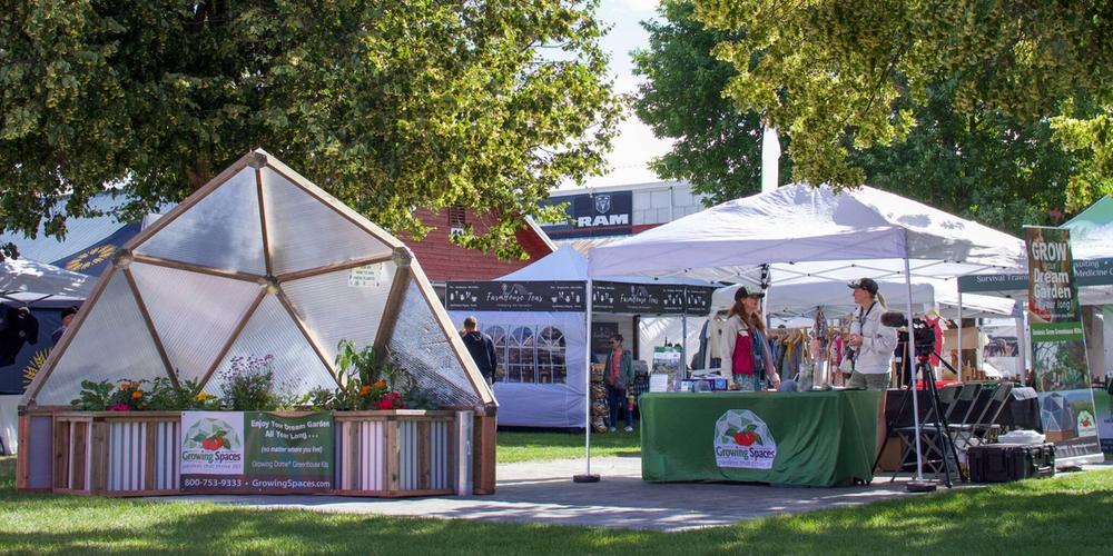 Booth with a partial growing dome model and a tent with two people standing in it talking to eachother
