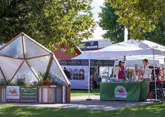 Booth with a partial growing dome model and a tent with two people standing in it talking to eachother