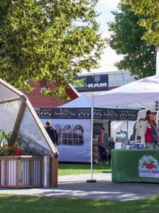 Booth with a partial growing dome model and a tent with two people standing in it talking to eachother