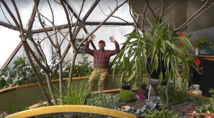 Man sitting in an insulated greenhouse during winter