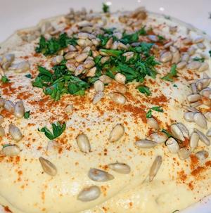 hummus dip topped with paprika sunflower seeds and parsley