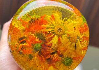 looking at the bottom of a jar with dried calendula flowers in oil