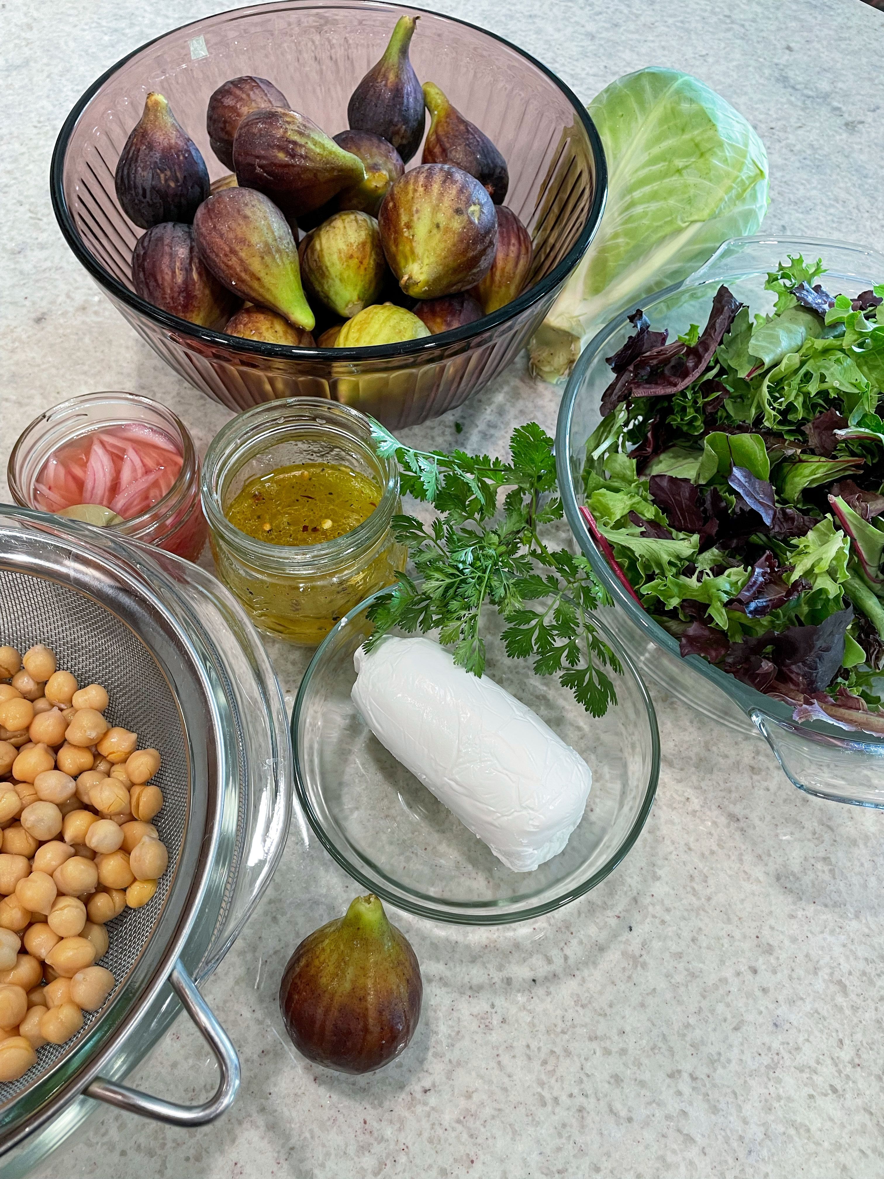 fig chickpea salad ingredients in bowls on granite countertop greens goat cheese pickled onions vinaigrette