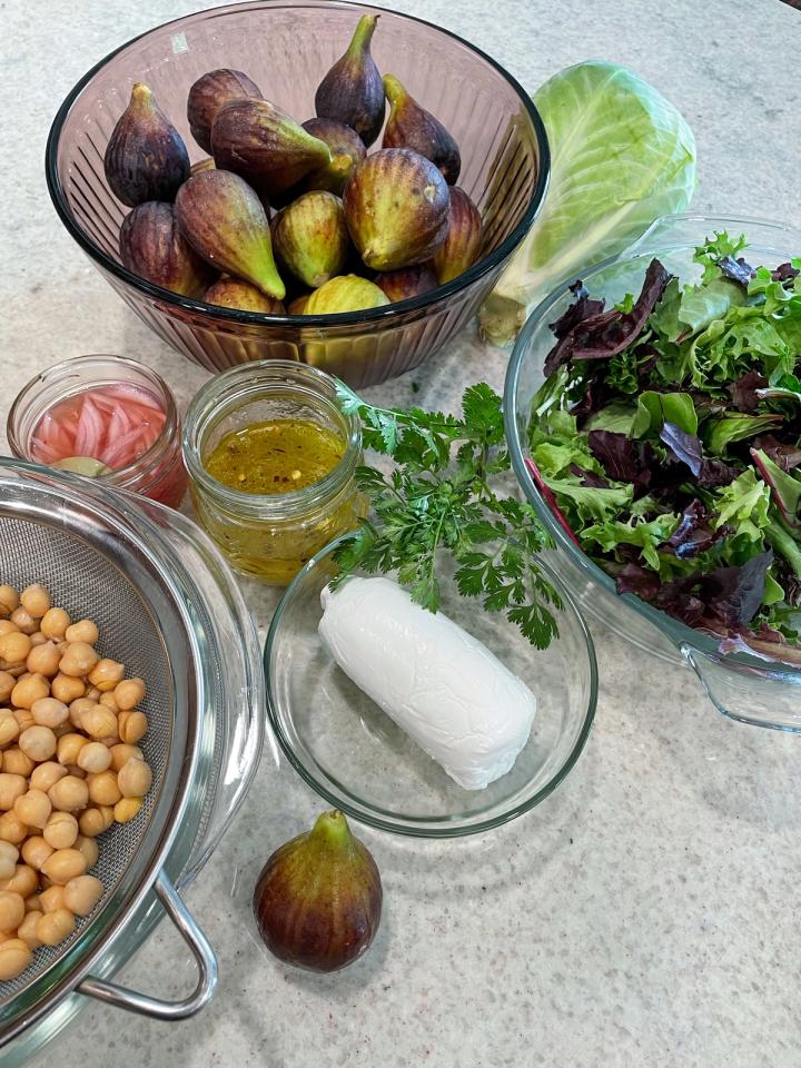 fig chickpea salad ingredients in bowls on granite countertop greens goat cheese pickled onions vinaigrette
