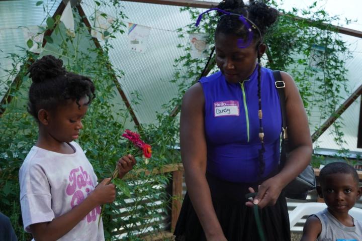 Younger sister looking to her older sister for guidance as she creates a flower bouquet in a greenhouse