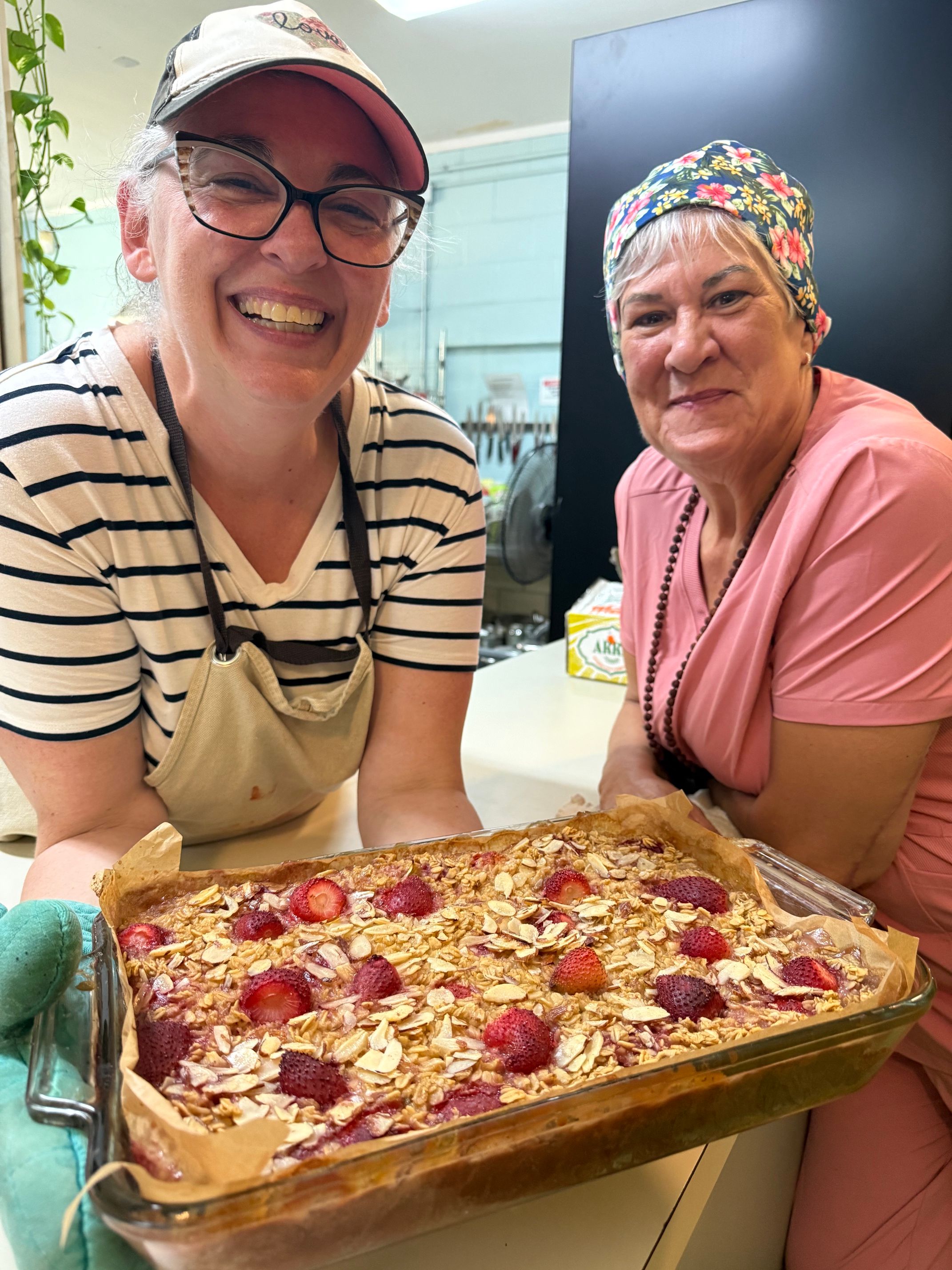 two smiling women showing off a dessert or dish they have prepared at Kula Kamala