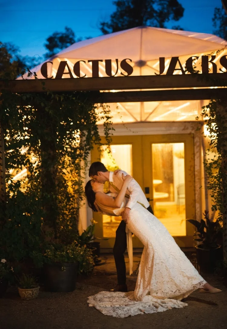 Wedding couple posing for a kiss in front of Cactus Jacks dome greenhouse bar