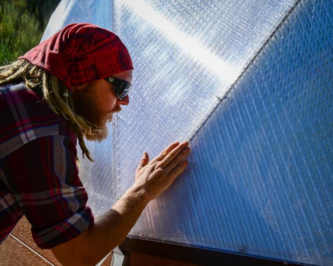 Crew member sealing a polycarbonate seam with aircraft tape on a Growing Dome greenhouse