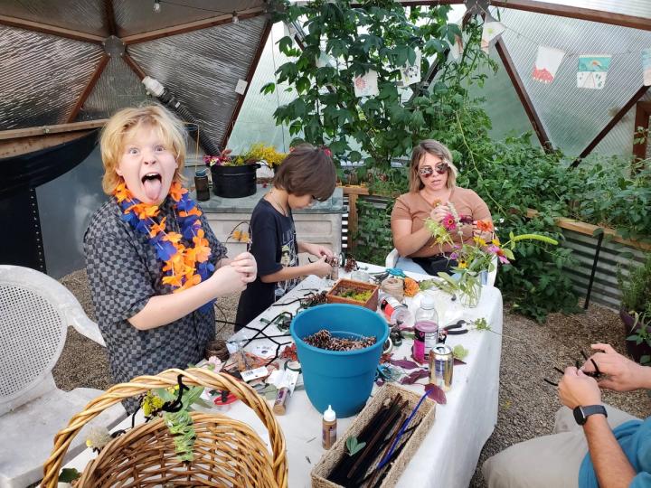 Kid working on an activity in a Growing Dome greenhouse making a funny face at the camera
