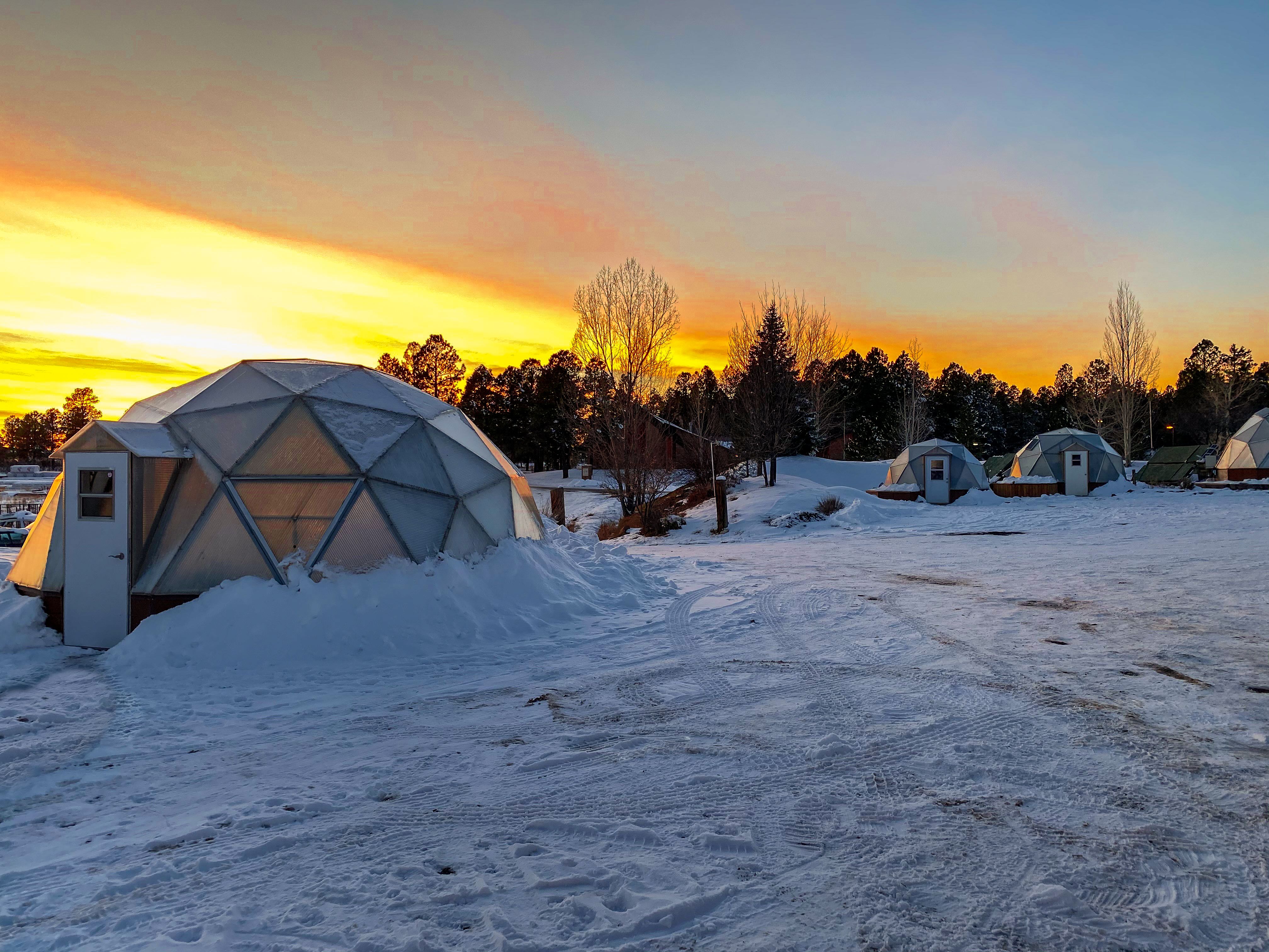 geodesic domes in the snow with sunrise in the background
